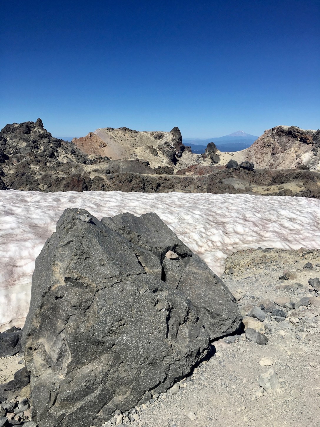 Volcanic boulder, permanent snowfield, caldera rim in Lassen Volcanic National Park