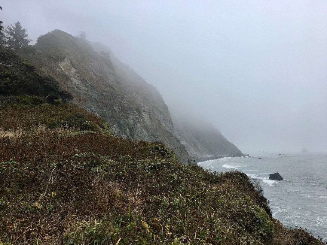 Rocky cliffs and pebble beach at the Pacific coast terminus of Damnation Creek Trail in Del Norte Coast Redwoods State Park